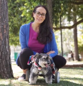 Doutora Thatiana Horn sentada no bosque com sua mascote Lurdinha